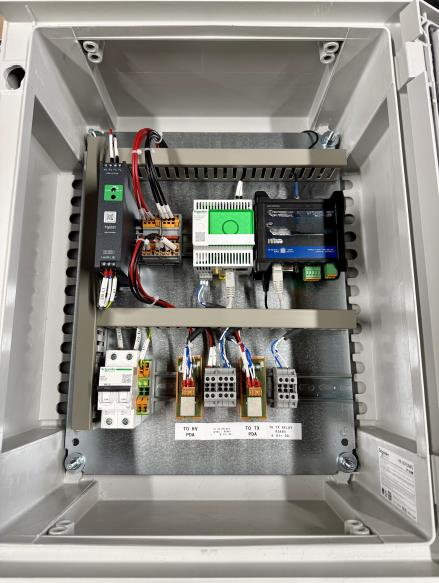 An open electrical control panel box showing various components, including fuses, wiring, terminal blocks, and electronic modules, organized neatly inside the enclosure.